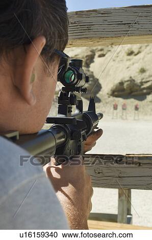 Stock Image - Man aiming rifle at firing range. Fotosearch