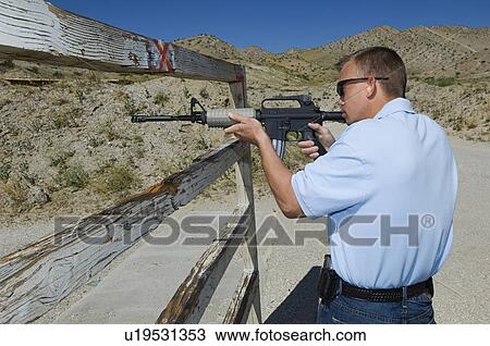 Man aiming rifle at firing range View Large Photo Image Stock Image - Man aiming rifle at firing range. Fotosearch