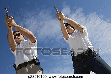 Man and woman aiming hand guns at firing range, low angle view View Large Photo Image Stock Image - Man and woman aiming hand guns at firing range, low angle view. Fotosearch