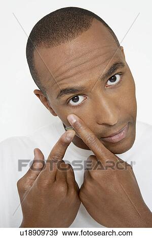 Stock Photo - Man applying contact lens, portrait. Fotosearch