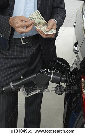 Man counting money over gas pump in car, mid section View Large Photo Image Stock Photography - Man counting money over gas pump in car, mid section. Fotosearch