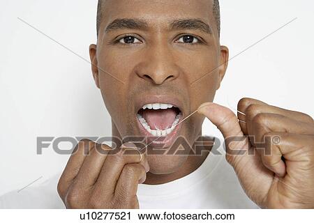 Stock Image - Man flossing teeth, portrait. Fotosearch