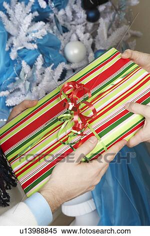 Stock Photography - Man handing woman present, close up of hands. Fotosearch