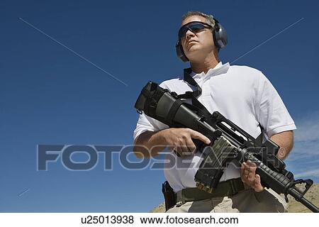 Man holding machine gun at firing range, low angle view View Large Photo Image Stock Photo - Man holding machine gun at firing range, low angle view. Fotosearch