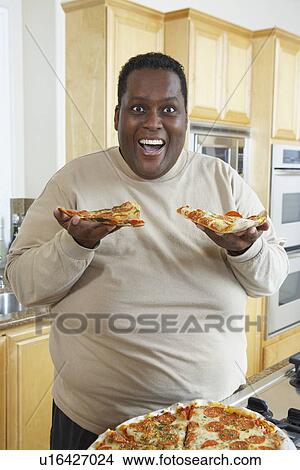 Picture - Man holding slices of pizza and laughing. Fotosearch