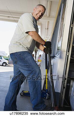 Man Jacking up Vehicle in Service Station View Large Photo Image Stock Photography - Man Jacking up Vehicle in Service Station. Fotosearch