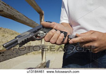 Man loading magazine into gun at firing range, close-up View Large Photo Image Stock Image - Man loading magazine into gun at firing range, close-up. Fotosearch