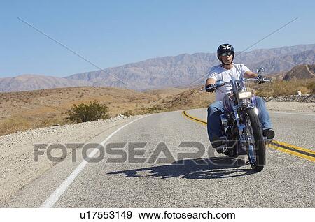 Man riding motorcycle on desert road View Large Photo Image Stock Photo - Man riding motorcycle on desert road. Fotosearch