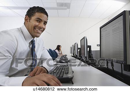 Stock Image - Man sitting at desk in front of computer. Fotosearch