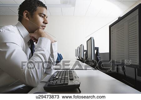Man sitting at desk in front of computer View Large Photo Image Stock Image - Man sitting at desk in front of computer. Fotosearch