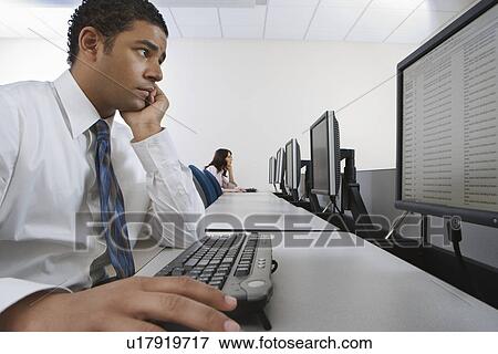 Man sitting at desk in front of computer View Large Photo Image Stock Photo - Man sitting at desk in front of computer. Fotosearch