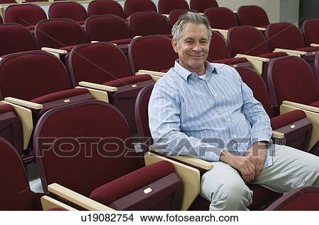 Picture - Man sitting in auditorium chair, portrait, elevated view. Fotosearch