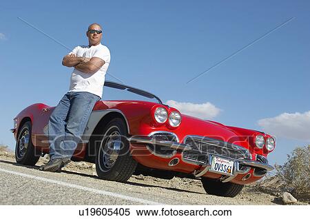 Man standing beside classic car on road View Large Photo Image Stock Photography - Man standing beside classic car on road. Fotosearch