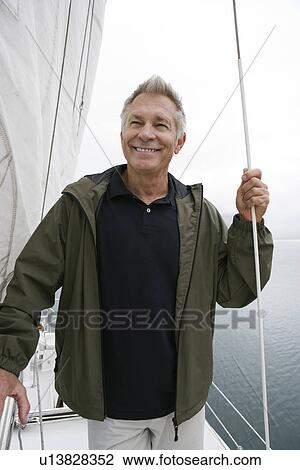 Stock Image - Man standing on yacht, portrait. Fotosearch