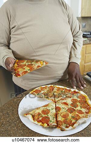 Man taking slice of pizza from kitchen counter View Large Photo Image Picture - Man taking slice of pizza from kitchen counter. Fotosearch