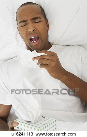 Stock Image - Man with flu in hospital bed. Fotosearch
