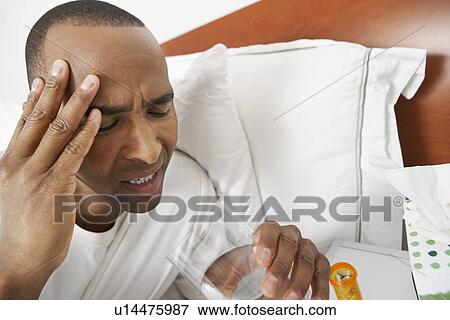 Stock Photo - Man with headache in hospital bed. Fotosearch
