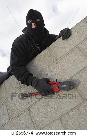 Picture - Masked thief climbing wall. Fotosearch