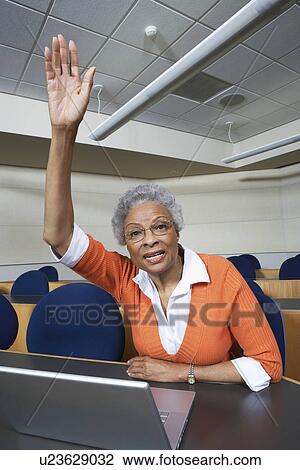 Mature female student raising hand in lecture theatre View Large Photo Image Stock Image - Mature female student raising hand in lecture theatre. Fotosearch