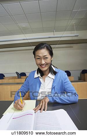 Stock Image - Mature female student working in lecture theatre, portrait. Fotosearch
