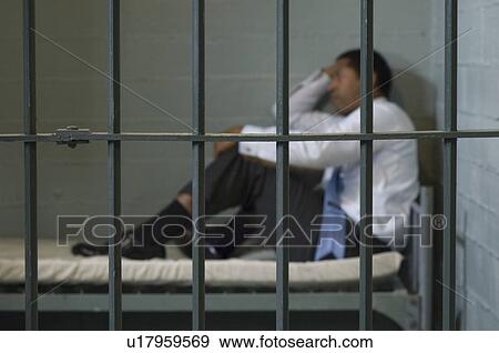 Stock Photo - Mature man sitting on bed in prison cell. Fotosearch