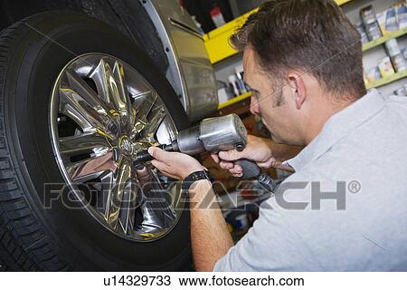 Stock Image - Mechanic Putting Tire on a Car. Fotosearch