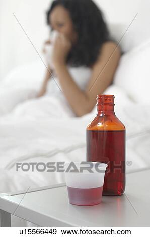 Stock Photo - Medicine on bedside table beside woman in bed. Fotosearch