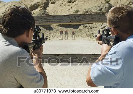 Stock Image - Men aiming rifles at firing range. Fotosearch