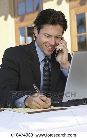 Mid adult business man writing while talking on phone outdoors View Large Photo Image Stock Image - Mid adult business man writing while talking on phone outdoors. Fotosearch