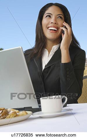Mid adult business woman talking on phone in front of laptop View Large Photo Image Stock Photography - Mid adult business woman talking on phone in front of laptop. Fotosearch