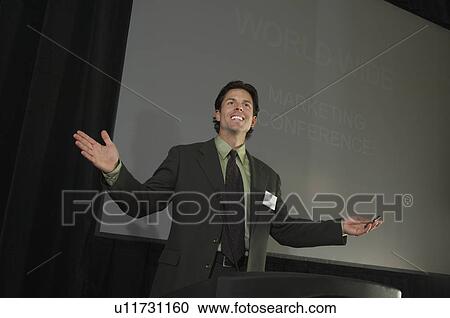 Stock Image - Mid adult man during presentation at conference. Fotosearch