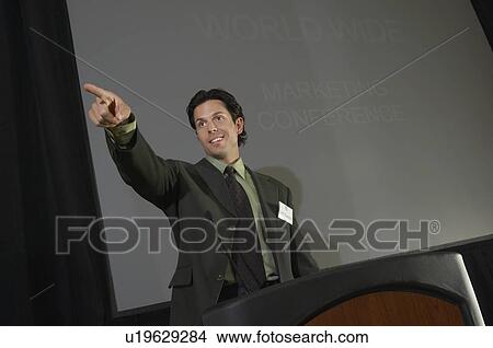 Picture - Mid adult man pointing during presentation at conference. Fotosearch