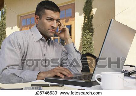 Mid adult man working on laptop at outdoor cafe table View Large Photo Image Stock Photo - Mid adult man working on laptop at outdoor cafe table. Fotosearch