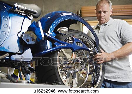 Mid-adult mechanic repairing motorcycle View Large Photo Image Stock Photograph - Mid-adult mechanic repairing motorcycle. Fotosearch