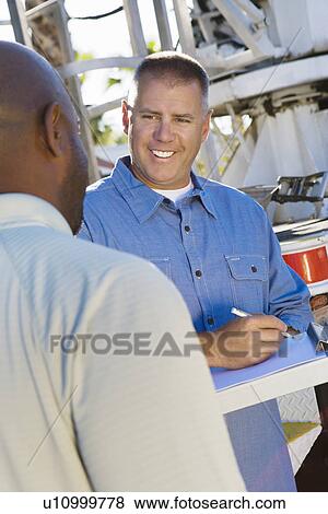 Mid-adult mechanic talking to co-worker View Large Photo Image Stock Photo - Mid-adult mechanic talking to co-worker. Fotosearch