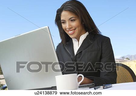 Stock Photo - Mid adult woman working on laptop outdoors. Fotosearch