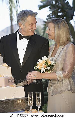 Middle-aged couple cutting wedding cake, portrait View Large Photo Image Stock Photo - Middle-aged couple cutting wedding cake, portrait. Fotosearch