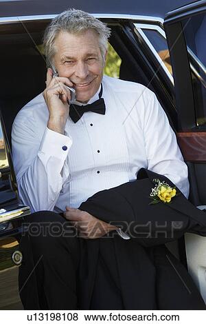 Middle-aged man talking on mobile phone in open door of limousine, portrait View Large Photo Image Stock Photo - Middle-aged man talking on mobile phone in open door of limousine, portrait. Fotosearch