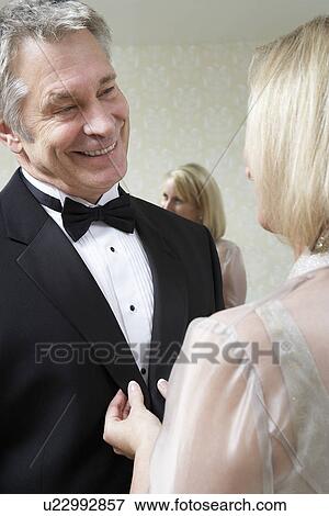 Stock Photo - Middle-aged woman buttoning husband's tuxedo jacket. Fotosearch