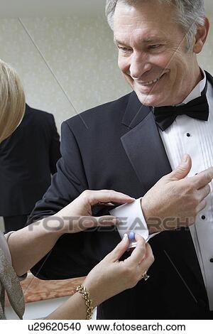 Stock Image - Middle-aged woman fastening husband's cufflink. Fotosearch