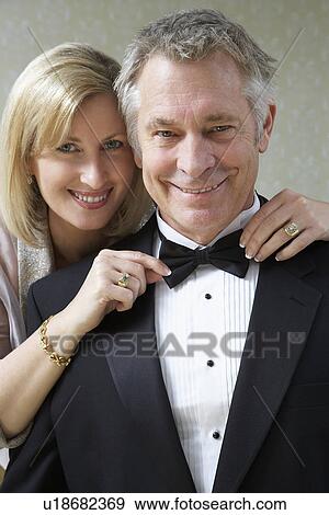 Stock Photo - Middle-aged woman tying husband's bow tie, portrait. Fotosearch