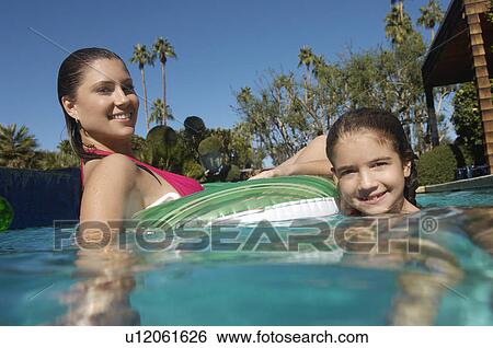 Mother and daughter floating on raft in swimming pool, portrait View Large Photo Image Stock Photograph - Mother and daughter floating on raft in swimming pool, portrait. Fotosearch