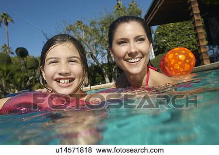 Stock Photo - Mother and daughter smiling in swimming pool, portrait. Fotosearch