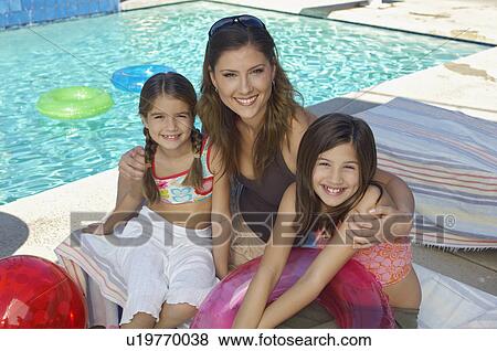 Mother embracing two daughters by swimming pool, portrait View Large Photo Image Stock Photo - Mother embracing two daughters by swimming pool, portrait. Fotosearch