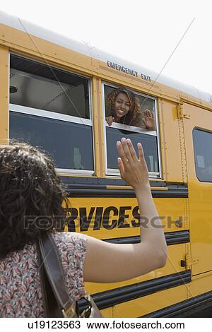 Stock Image - Mother Waving to Teenage Daughter on School Bus. Fotosearch