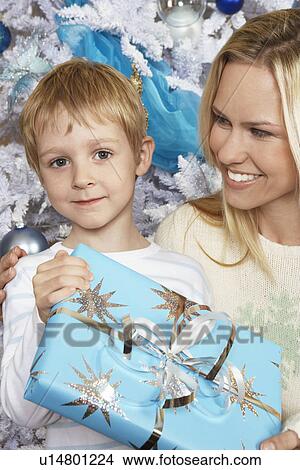 Picture - Mother with arm around boy (5-6) holding Christmas present. Fotosearch