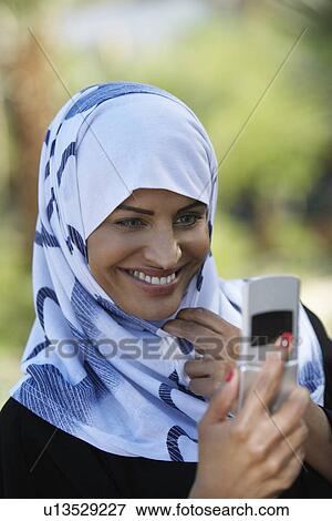 Muslim woman using mobile phone View Large Photo Image Stock Photo - Muslim woman using mobile phone. Fotosearch