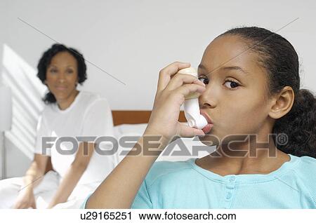 Stock Image - Nurse watching girl (7-9) using inhaler in hospital. Fotosearch