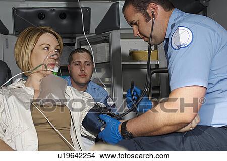 Picture - Paramedics taking care of victim in ambulance. Fotosearch