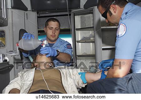 Stock Image - Paramedics taking care of victim in ambulance. Fotosearch